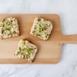 Drei vegane Flammkuchen-Toasts auf Holzbrett – knusprige Apéro-Häppchen mit Räuchertofu, Sauerrahm und Frühlingszwiebeln, von oben fotografiert