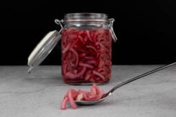 Red Onion Pickles fertig im Glas mit Onions auf dem Loeffel