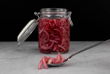 Red Onion Pickles fertig im Glas mit Onions auf dem Loeffel