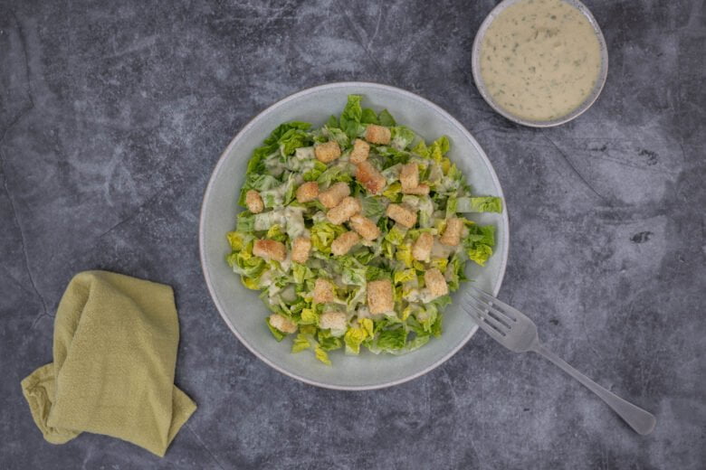 caesar salad auf teller mit sauchen schaelchen
