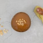 erdnuss sauce in schale mit holzloeffel und nuessen