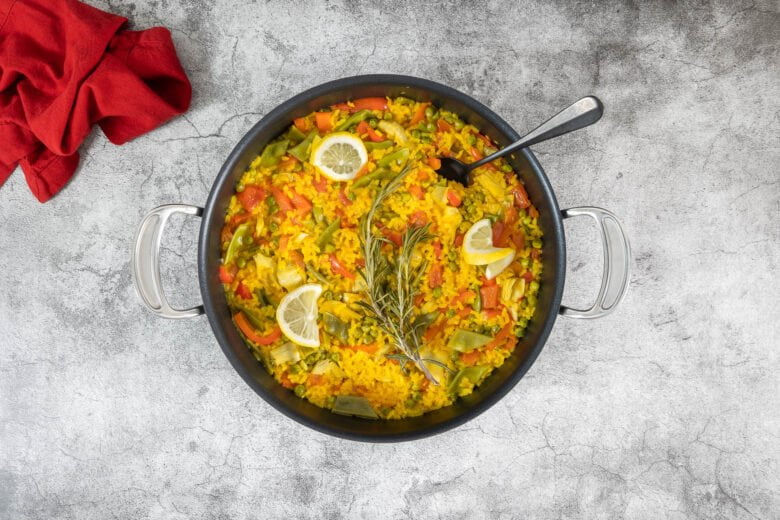 Vegane Paella mit Gemüse mit Löffel uns Serviette