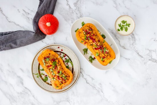 Oreintalischer Kürbis mit Couscous und Granatapfel auf zwei Tellern