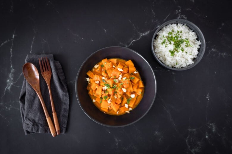 Veganes Kuerbis Curry mit Holzbesteck in zwei Tellern