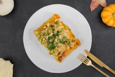 Schnelle Cannelloni mit Kürbisfüllung mit Besteck Serviette und Kürbis