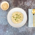 Veganes Risotto auf dem Teller mit Löffel und veganem Parmesan