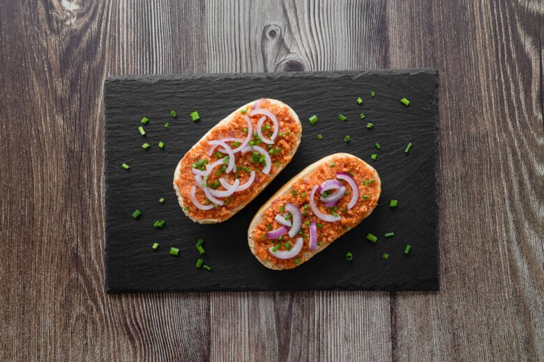 Veganes Mett auf schwarzer Platte angerichtet auf dem Brötchen