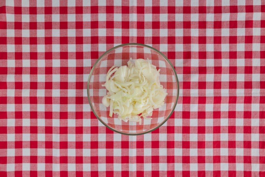 Geschnittene Zwiebelringe für Röstzwiebeln – Vorbereitung für cremige vegane Älplermagronen mit Apfelmus