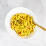 Hoernlisalat vegan - der Beste Nudel-Curry Salat der Schweiz im Teller mit goldenem Loeffel