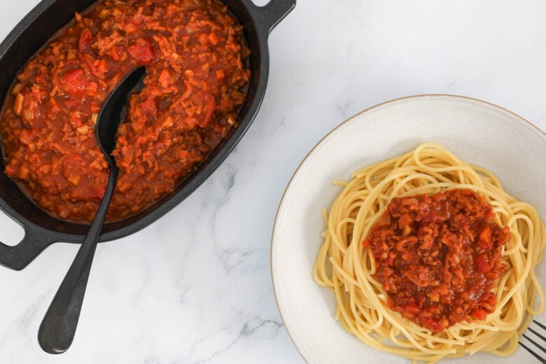 Vegane Bolognese Pasta Sauce in Schale mit Teller und Bolognese Sauce auf Spaghetti
