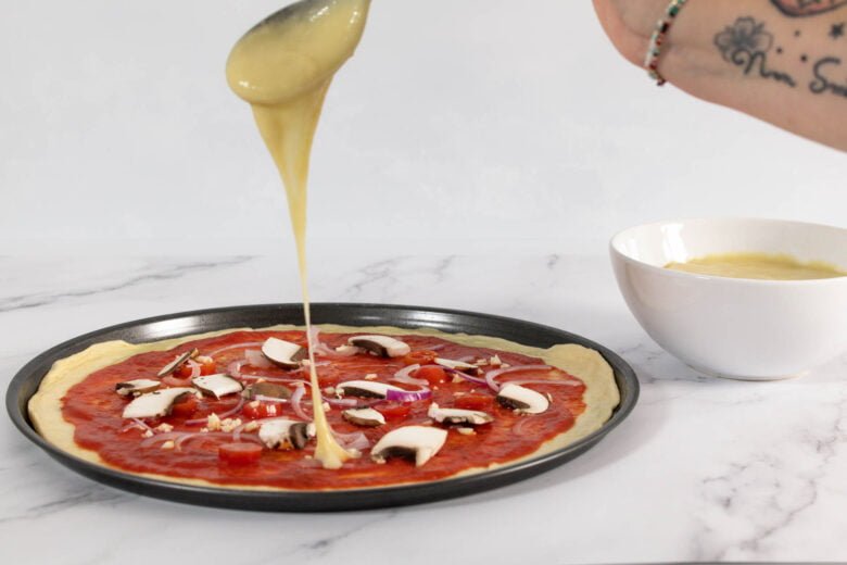 Veganer Mozarella wird auf die Pizza gegeben