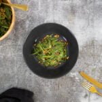 Bohnensalat mit Ingwer und Erdnuessen auf schwarzem Teller