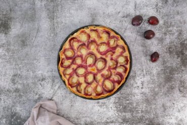 Vegane Zwetschgenwaehe mit Zwetschgen auf dem Tisch