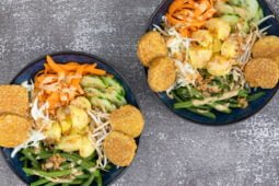 Tempeh mit Gartoffel, Bohne, Gurke, Karotte und Erdnusssauce in zwei Tellern