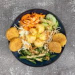 Tempeh mit Gartoffel, Bohne, Gurke, Karotte und Erdnusssauce im Teller