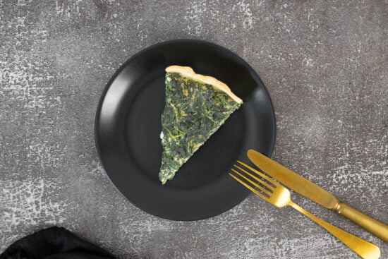 Vegane Spinatwaehe ein Stück auf dem Teller mit Besteck