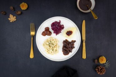 Veganer Wildteller - Kastanien Spätzli Wild mit Rotkraut und Herbstdekoration und Saucenschale auf dem Tisch