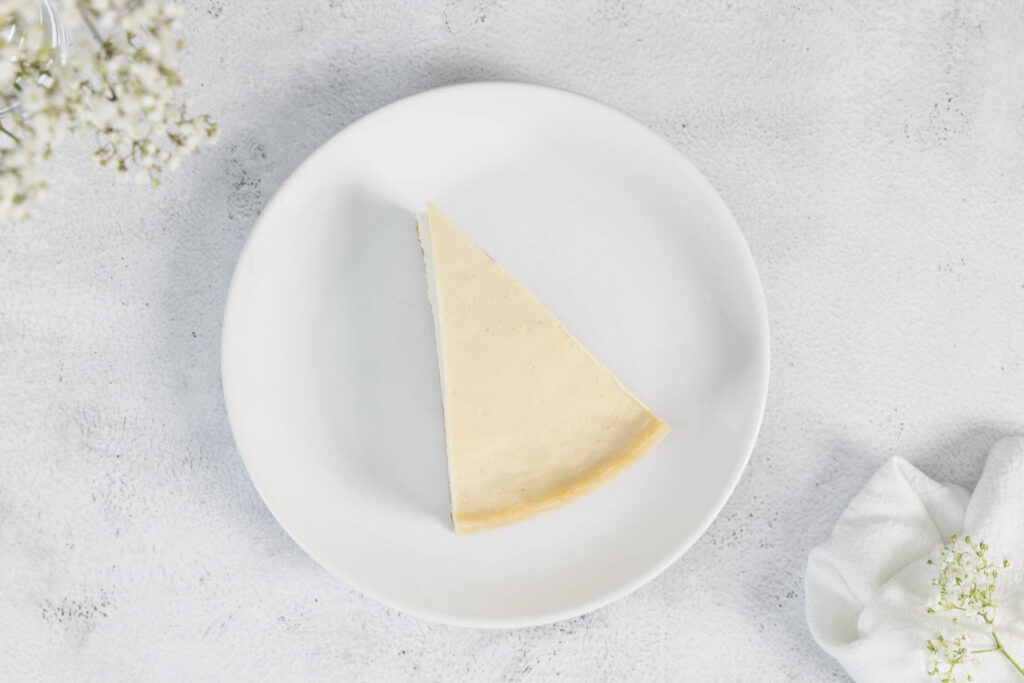 Originaler New York Cheesecake Vegan ein Stück von oben mit Blümchen auf dem Tisch