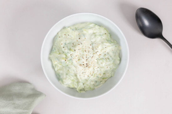 Veganes Tzaziki mit Joghurt im Schüssel mit Serviette und Löffel