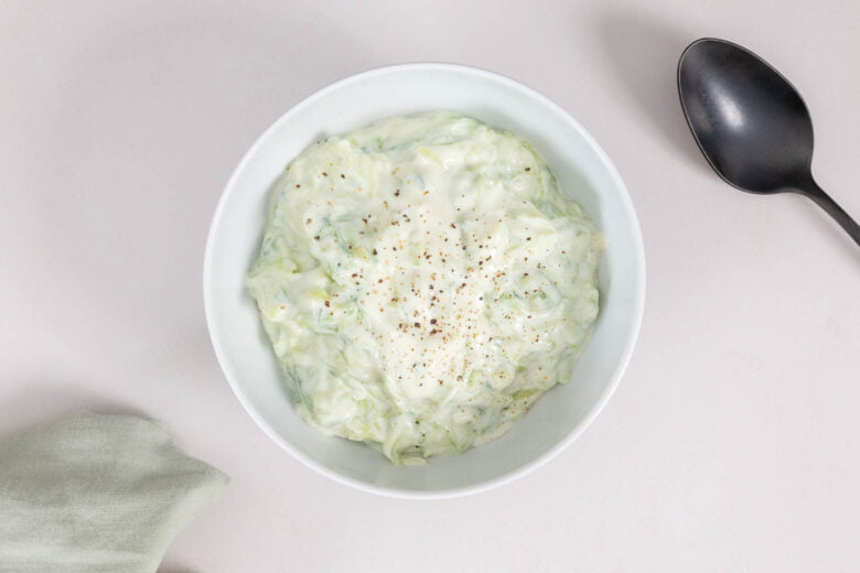 Veganes Tzaziki mit Joghurt im Schüssel mit Serviette und Löffel