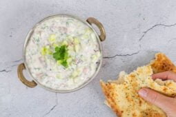 Veganes Raita - indische Joghurtsauce mit Gurke und Tomate alle Zutaten werden in die Schüssel gegeben beim Kochen