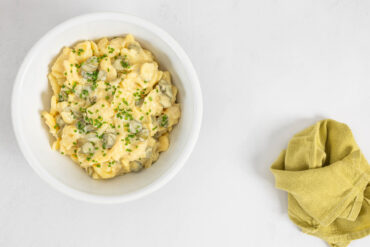 Veganer Kartoffelsalat - Der beste Härdöpfelsalat der Welt - auf einem Teller auf dem Tisch mit Serviette