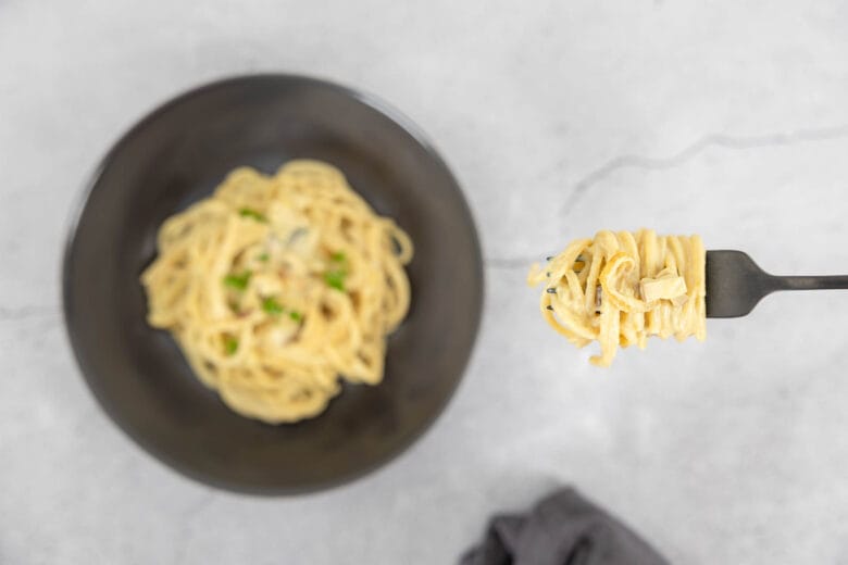 Vegane Spaghetti Carbonara mit Seidentofu auf dem Teller mit Gabel die isst