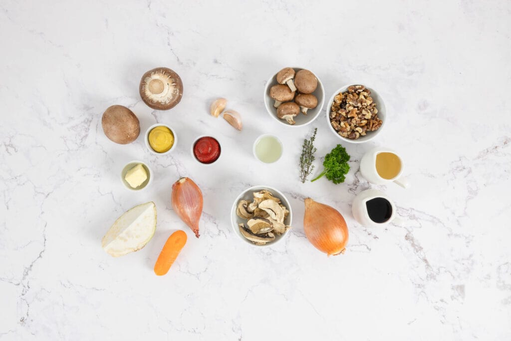 Veganes Pilz Wellington - Zwiebel, Schalotte, Karotte, Sellerie, Nüsse, Pilze auf dem Tisch