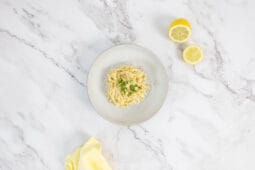 Vegane Zitronenpasta mit Petersilie und Pfeffer, serviert mit frischer halbierter Zitrone – Tagliatelle al Limone vegan