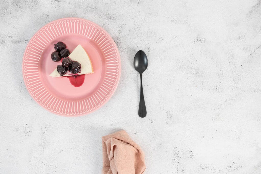Veganer No-Bake Cheesecake mit Zuger Kirschen auf dem rosa Teller
