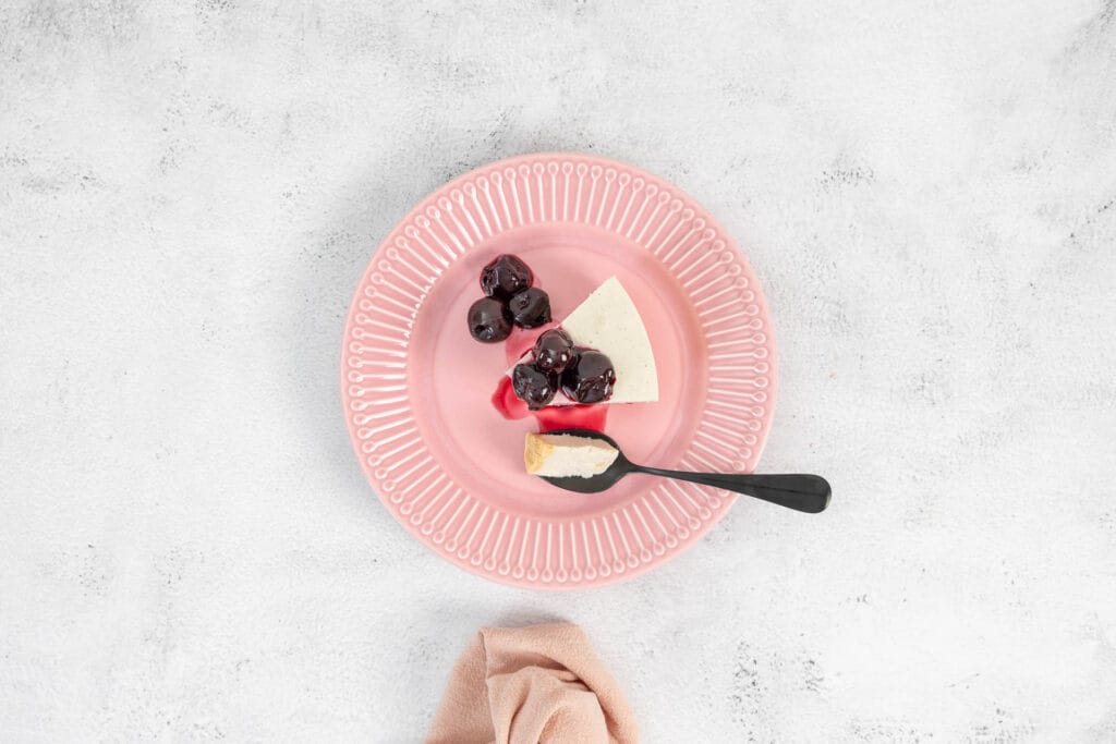 Veganer No-Bake Cheesecake mit Zuger Kirschen auf dem rosa Teller