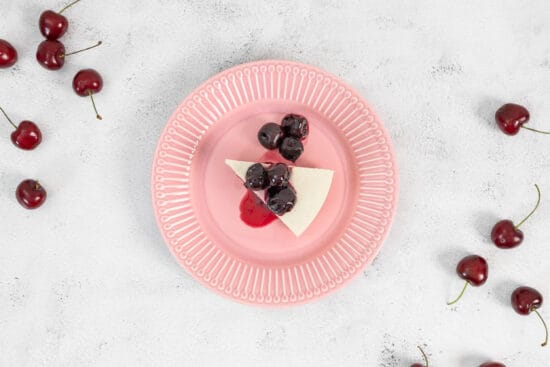 Veganer No-Bake Cheesecake mit Zuger Kirschen auf dem rosa Teller