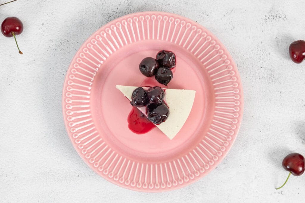 Veganer No-Bake Cheesecake mit Zuger Kirschen auf dem rosa Teller