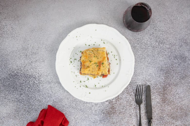 Stück authentisches veganes Moussaka mit Rotwein serviert