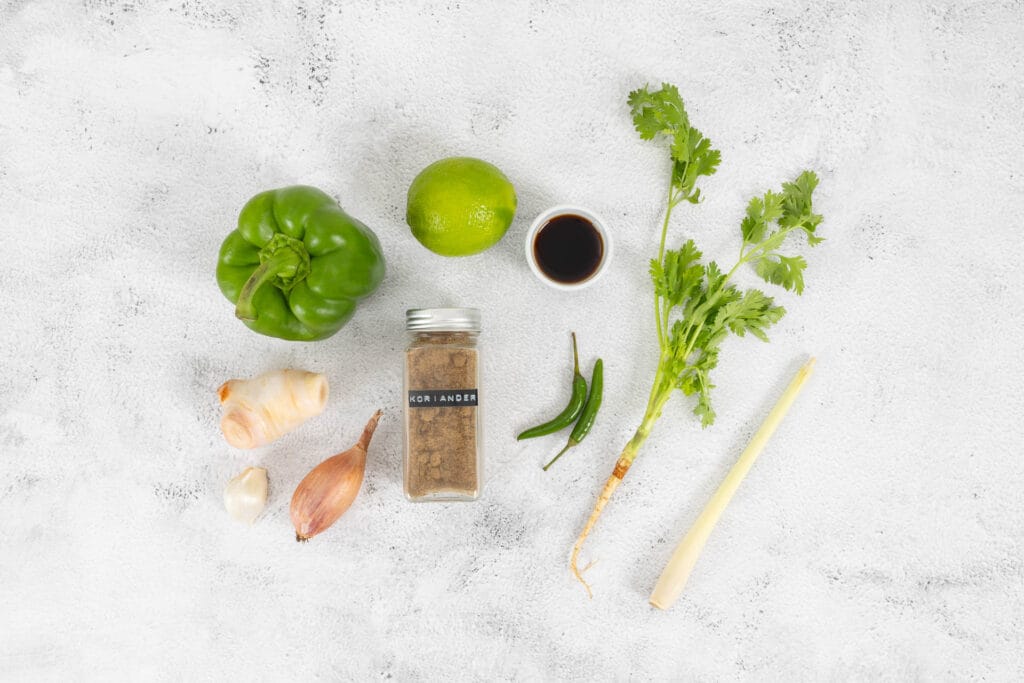 Zutaten für grüne Thai-Currypaste vegan – Zitronengras, grüne Chili, Galgant, Koriander und Limette von oben fotografiert