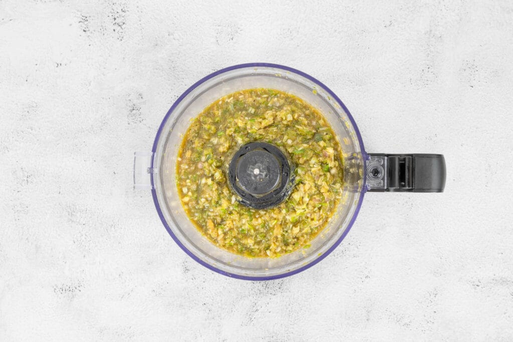 Zerkleinerte Zutaten für grüne Thai-Currypaste im Foodprocessor während der Verarbeitung, selber machen vegan