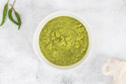 Frisch gemachte grüne Thai-Currypaste vegan in einer Schüssel, daneben grüne Thai-Chilis, Nahaufnahme von oben