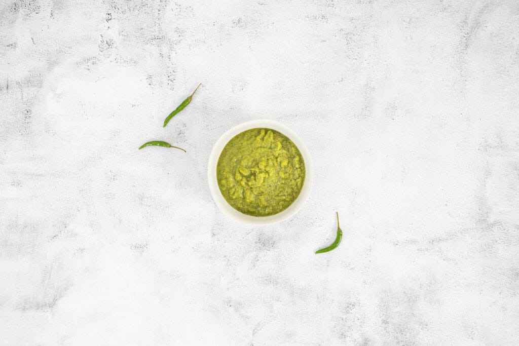 Selbstgemachte grüne Currypaste vegan in einer Schüssel mit Thai-Chilis, Rezeptaufnahme von oben fotografiert