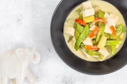 Nahaufnahme: Grünes Thai Curry vegan, Elefanten-Statue im Hintergrund – Kokosmilch, Makrut-Limette, schnell gekocht