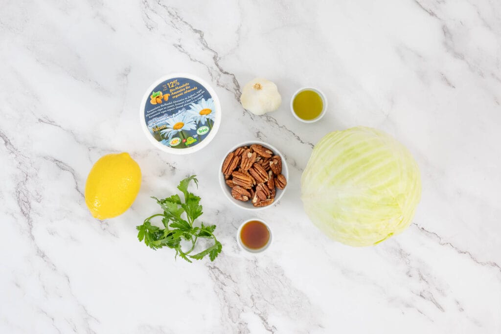 Zutaten für mediterrane Kabisspalten aus dem Ofen mit Weisskohl, Olivenöl, Zitrone und Mandel-Joghurt