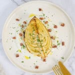 Nahaufnahme Ofenkohlspalten auf Joghurtsauce mit Petersilie und gebrannten Nüssen, Besteck am Teller