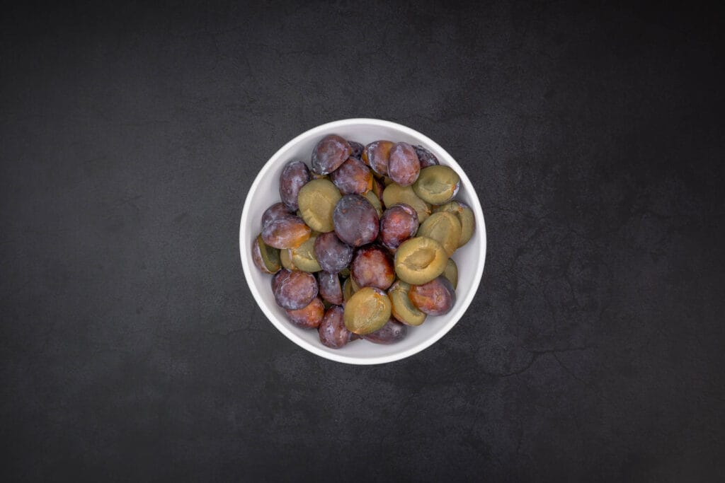 Halbierte Zwetschgen in einer Schüssel – perfekte Früchte zum Einmachen und Einkochen in Rotwein