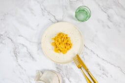 Kürbispasta im Teller, daneben Glas Wasser und Besteck – sanfte Alfredo-Interpretation mit Kürbis und Muskat