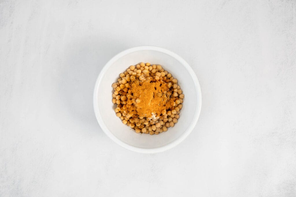 Kichererbsen mit Gewürzen in Schale – Vorbereitung für knusprige Kichererbsen-Tacos mit Paprika und Kreuzkümmel