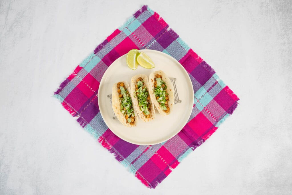 Fertige Kichererbsen-Tacos im Taco-Ständer auf Teller mit mexikanischer Serviette – einfaches 30-Minuten-Rezept mit Airfryer