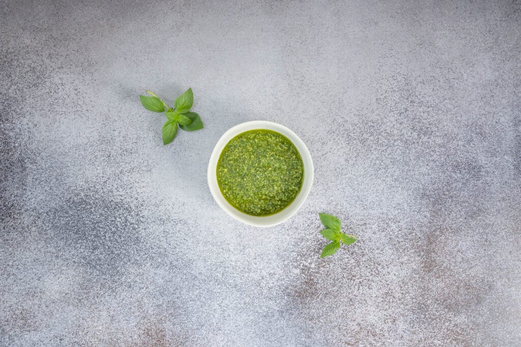 Schüssel mit frisch gemachtem Basilikum-Pesto ohne Parmesan, daneben Basilikumblätter – klassisches italienisches Rezept in vegan