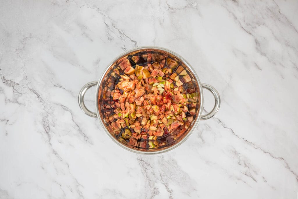 Geschnittene Feigen in Portwein in einer Pfanne – Beginn der Zubereitung für Feigenkonfitüre mit Portwein und Gewürzen