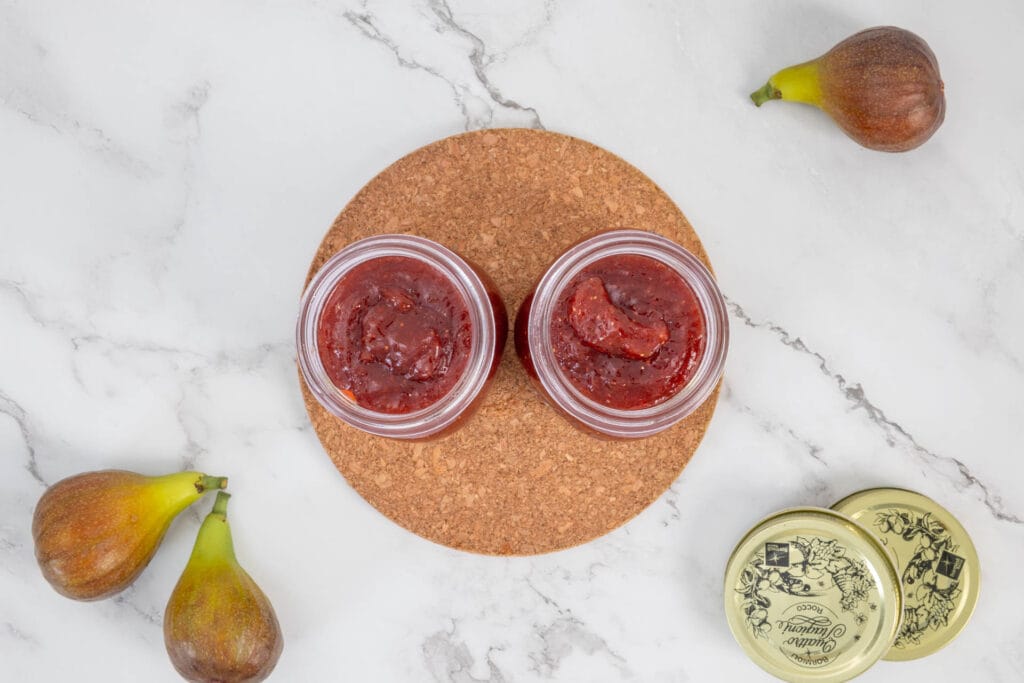 Feigenkonfitüre in Gläsern mit frischen Feigen drumherum – Feigenmarmelade im Glas, fertig abgefüllt