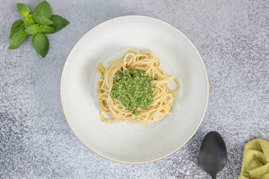 Nahaufnahme Spaghetti mit Basilikum-Pesto vegan – cremige grüne Sauce aus frischem Basilikum, Olivenöl und Hefeflocken