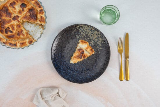 Ein Stück veganer Pilz Pot Pie auf Teller mit Glas Wasser – herbstliches Comfort Food